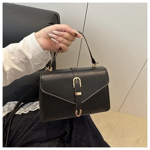 Detailed shot of black minimalist handbag with gold buckle and smooth leather texture
