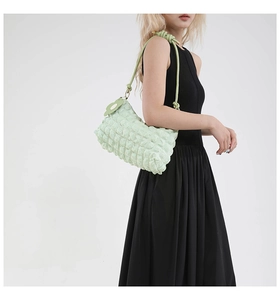 Detail view of light green bubble bag with 3D texture and decorative flower pendant