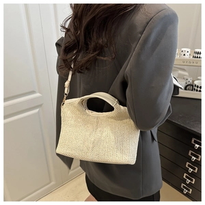 Detailed view of cream woven bucket bag styled with a dark gray suit for a chic daily look