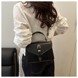 Model wearing black matte PU leather envelope handbag with a gold buckle and shoulder strap