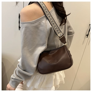 Detail of dark brown vintage pillow bag with adjustable geometric pattern webbing strap