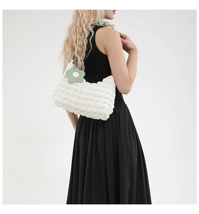 Detail of white bubble texture crossbody bag with green rope strap and flower charm