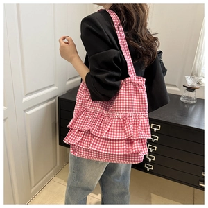 Detail of pink plaid canvas tote with tiered ruffles and wide shoulder strap on model