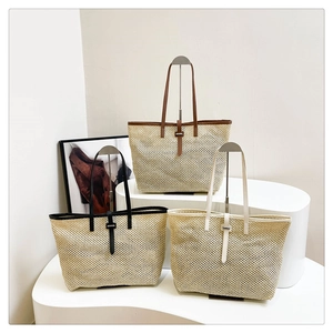 Three large woven tote bags in brown, black, and beige colors on display stands