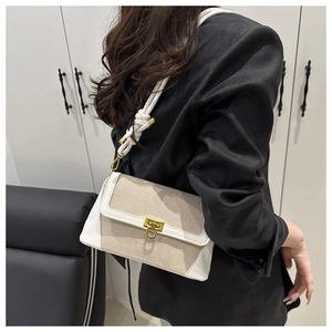 Détail d'un sac en toile beige avec finitions en cuir et fermoir doré élégant