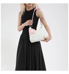 Detailed view of white bubble texture handbag with pink shoulder strap and flower charm