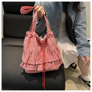Detail of red gingham tote bag featuring ruffle edges and drawstring closure for women