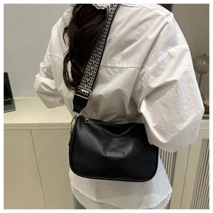 Detail of black PU leather pillow bag with stylish black and white geometric wide strap