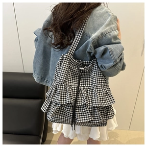 Detail of a black and white checkered tote bag featuring tiered ruffles and drawstring closure