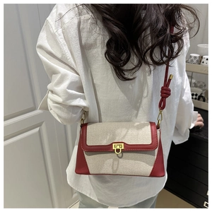 Détail du sac bandoulière en toile avec bordure en cuir rouge et fermoir doré