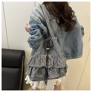 Detail of black and white gingham shoulder bag with ruffle layers and drawstring closure