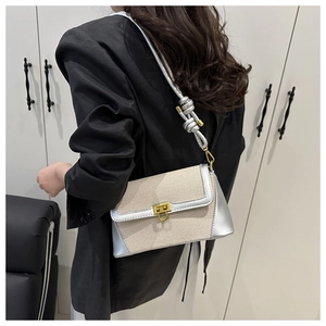 Détail du sac bandoulière en toile beige avec garniture miroir argentée et fermoir doré