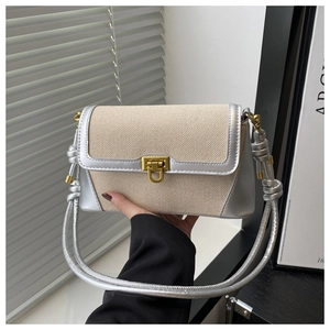 Détail du sac en toile tissée beige avec bordure argentée et boucle dorée chic