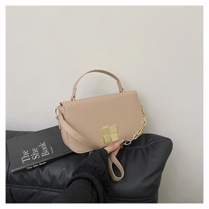 Detail van beige flap tas met een vierkante gouden metalen gesp en leren handvat textuur
