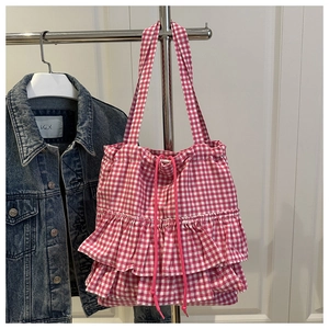 Detail of pink plaid tote bag featuring ruffled layers and a functional drawstring closure