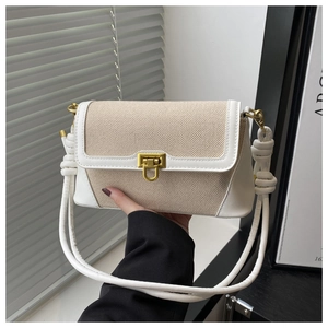 Détail du sac en toile avec garniture en cuir blanc, fermoir doré et bandoulière nouée