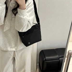 Minimalist black nylon crossbody bag for women featuring adjustable strap and metal logo