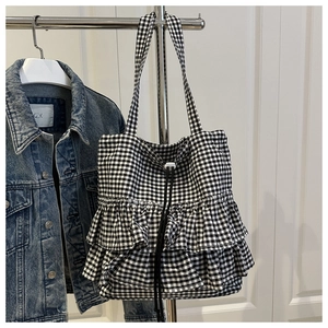 Detail of gingham tote bag featuring triple-layered ruffles and black handles on hanger