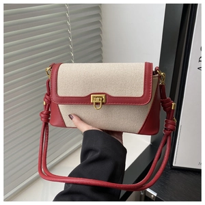 Détail des coutures, de la bandoulière en cuir rouge et boucle dorée sur un sac en toile