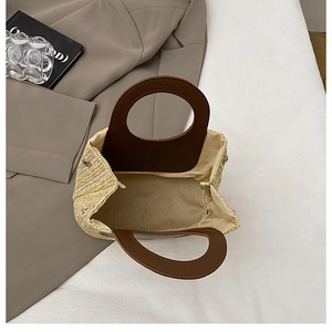 Detail view of woven straw bag with leather handles and magnetic snap closure