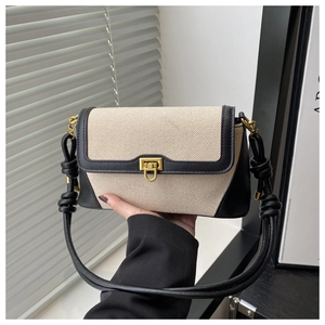 Détail d'un sac bandoulière en toile et cuir noir avec fermoir doré et nœud élégant