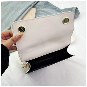 Détails d'un sac bandoulière blanc avec boucles magnétiques dorées et doublure noire