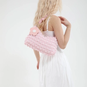Pink popcorn texture shoulder bag with floral pendant shown on model back view