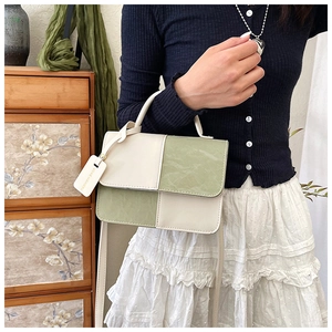 Détail du sac à main patchwork vert et beige avec surface texturée et breloque mode
