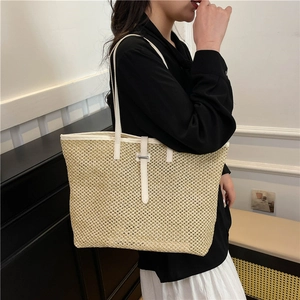 Fashionable woven tote bag in beige with white leather straps for summer beach vacation