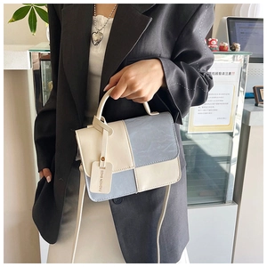 Détail du sac à bandoulière bicolore tendance en cuir crème et bleu avec étiquette