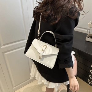 Elegant white leather crossbody bag with gold buckle shown on a model in a blazer