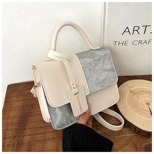 Détail du sac à main minimaliste beige et gris avec chaîne et étiquette de design chic