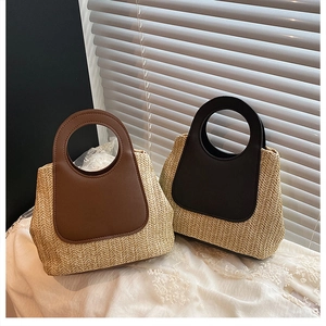 Detailed macro view of woven straw handbags with contrast leather stitching and handles