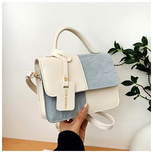 Détail du sac à bandoulière beige et bleu clair minimaliste avec texture froissée et étiquette