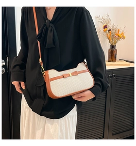 Dettaglio della borsa sottobraccio intrecciata bianca con fiocco in pelle marrone