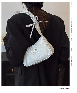 Detail of light blue pleated underarm bag featuring silver butterfly buckle and bow strap