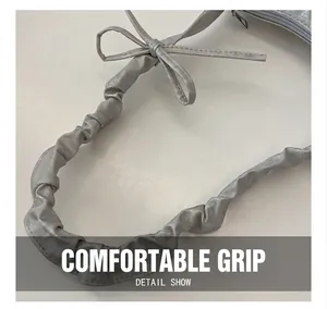 Detailed macro view of the pleated handle and silver butterfly knot on a modern bag