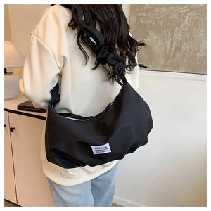 Detail of black pleated nylon cloud bag featuring a wide scrunchie strap and fashion label