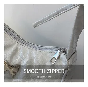 Detail shot of silver ruched handbag showing metallic texture and butterfly ornament