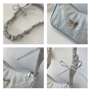Close-up of silver pleated shoulder bag featuring a metal butterfly and bow strap