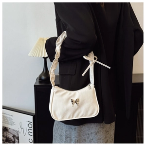 Detail of white pleated underarm bag with silver butterfly accent and ruffled strap