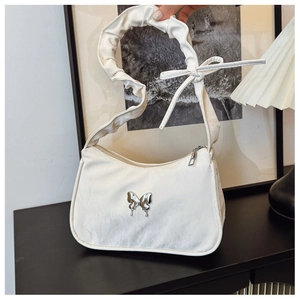 Close-up of pleated beige satin shoulder bag featuring a silver metal butterfly ornament
