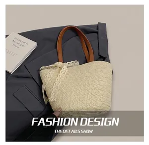 Detail of hand-woven straw tote bag featuring brown leather handles and white lace bow