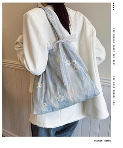Detail of light blue embroidered canvas bag with lace bow and floral texture