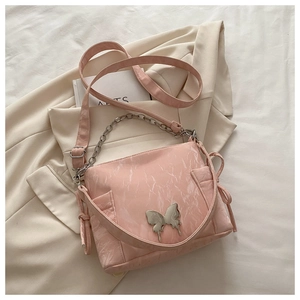 Detail of pink pleated handbag with silver butterfly charm and chain strap
