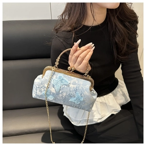 Detail of light blue embroidered shell bag with butterfly motif and golden handle