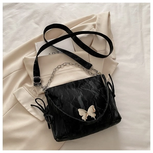 Detailed view of black wrinkled texture bag with silver chain and metal butterfly clasp