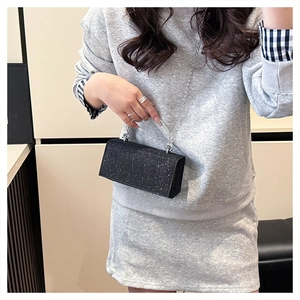 Detail of a black sequin mini square bag with silver chain strap and clear handle