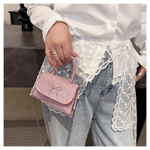 Close-up of a pink sequin handbag featuring a silver bow metal buckle and metal chain