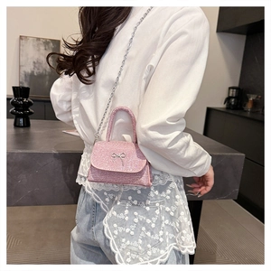 Close-up of pink sequined handbag with silver bow detail and delicate chain strap